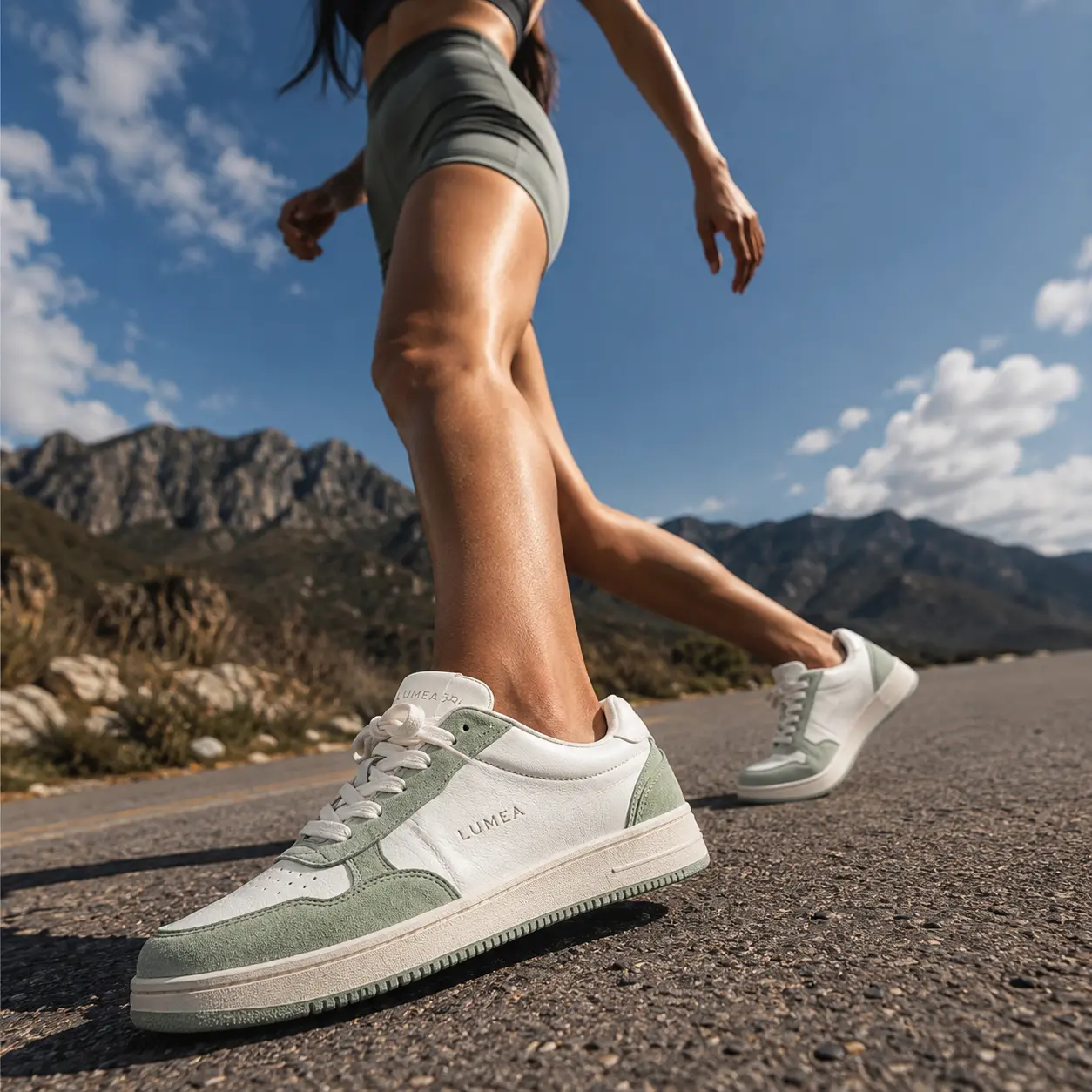 Campaign photo of the white and sage sneakers in motion on a mountain road