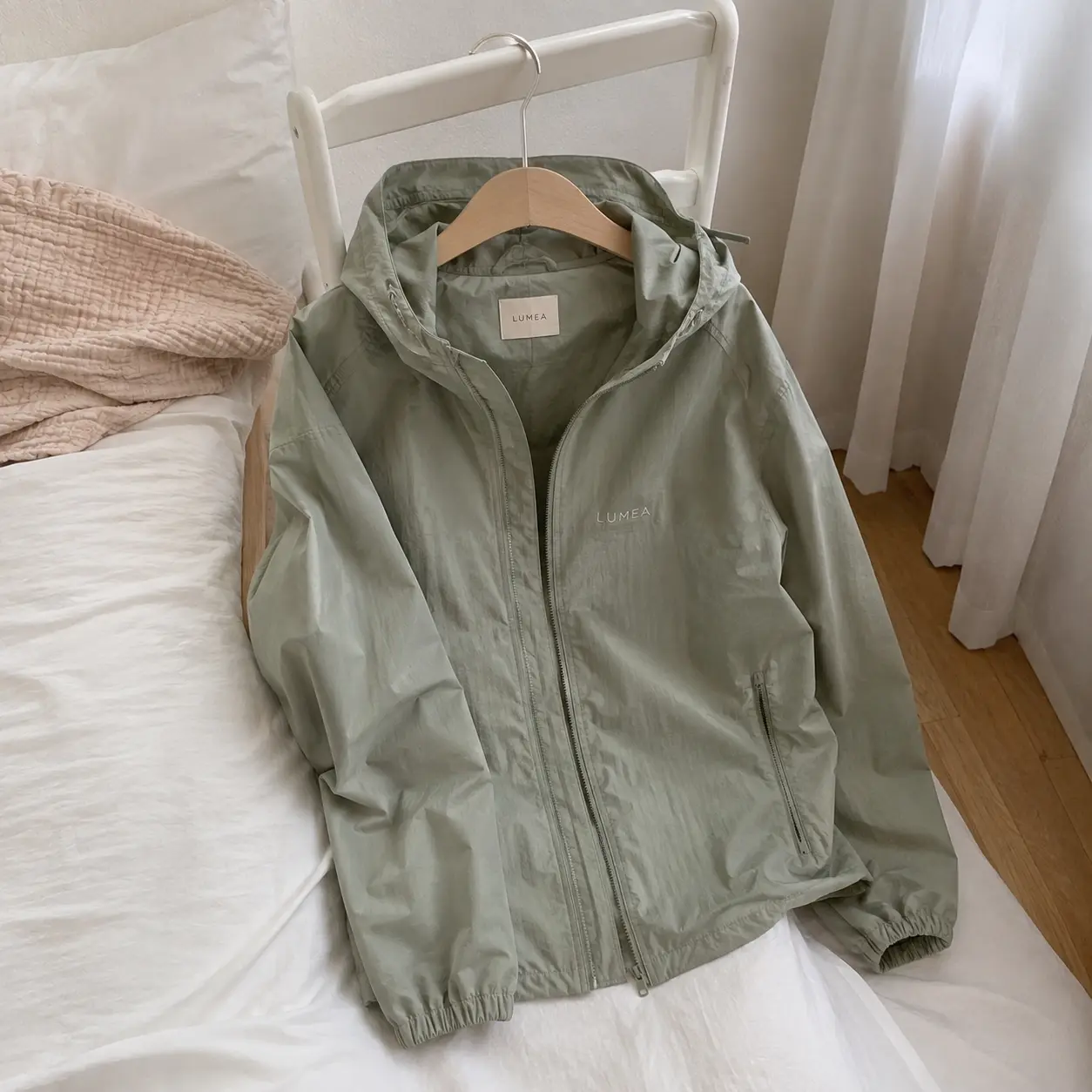 Phone photo of a sage green jacket on a hanger in a bedroom