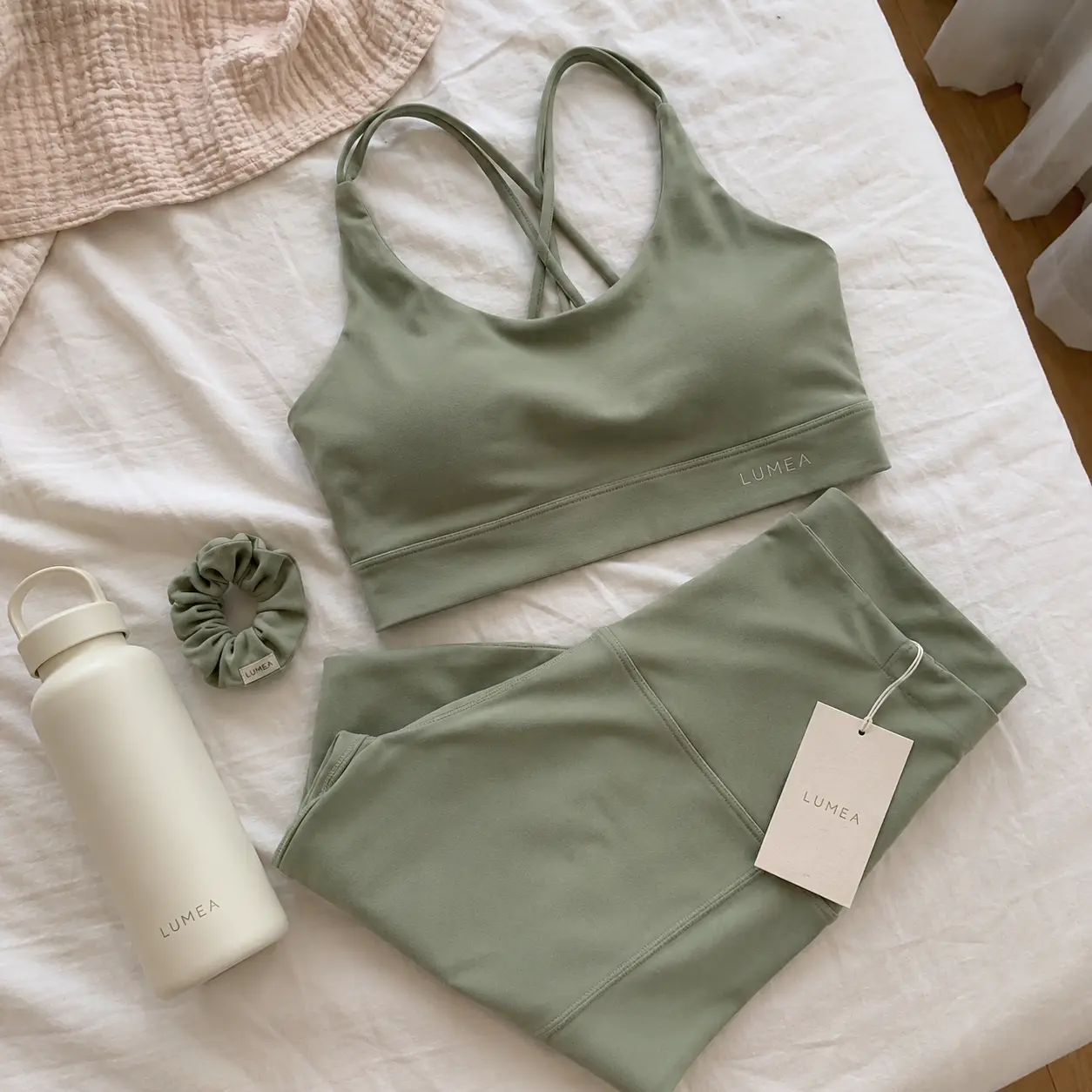 Phone photo of a sage green sports bra and leggings set laid on a bed