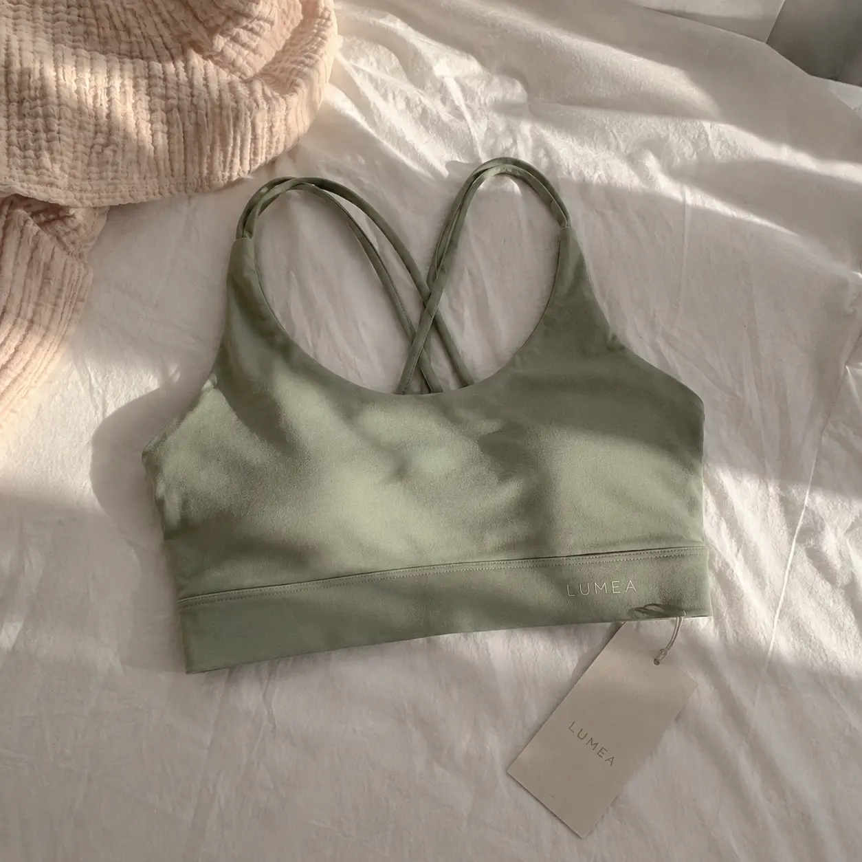 Blurry phone photo of a sage green sports bra in harsh window light