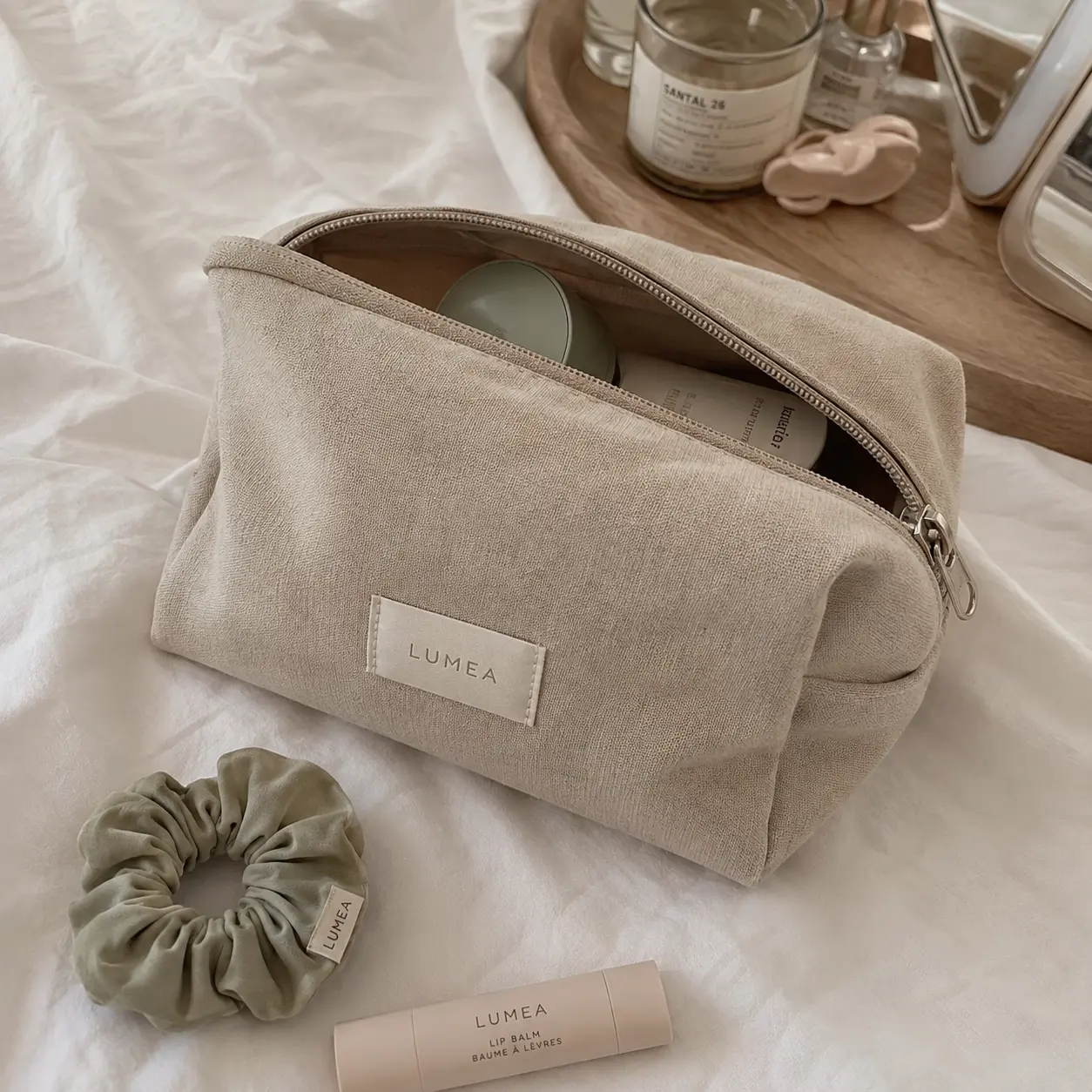 Phone photo of a linen cosmetic pouch, scrunchie and lip balm on a bed